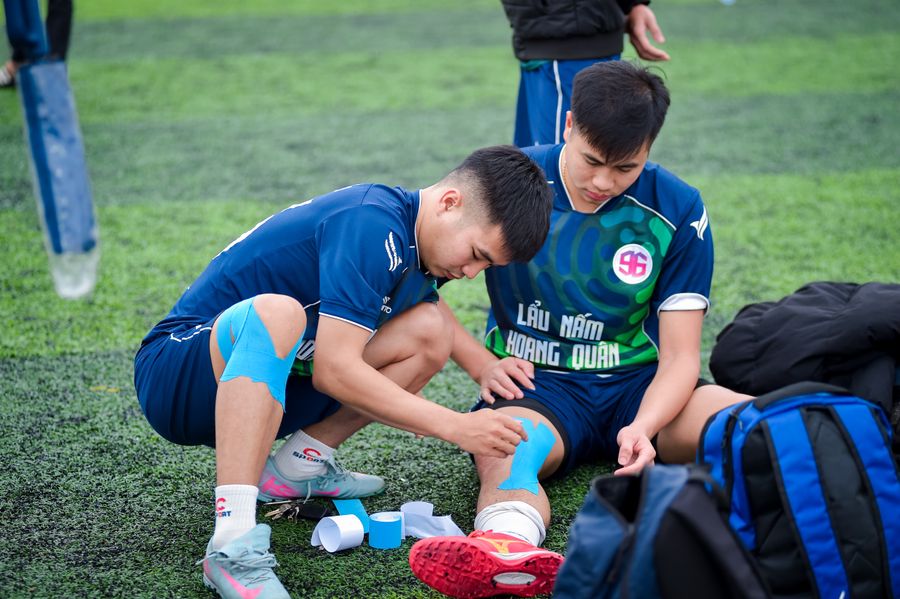 Fisioterapeuta deportivo vendando la rodilla de un atleta sobre pasto